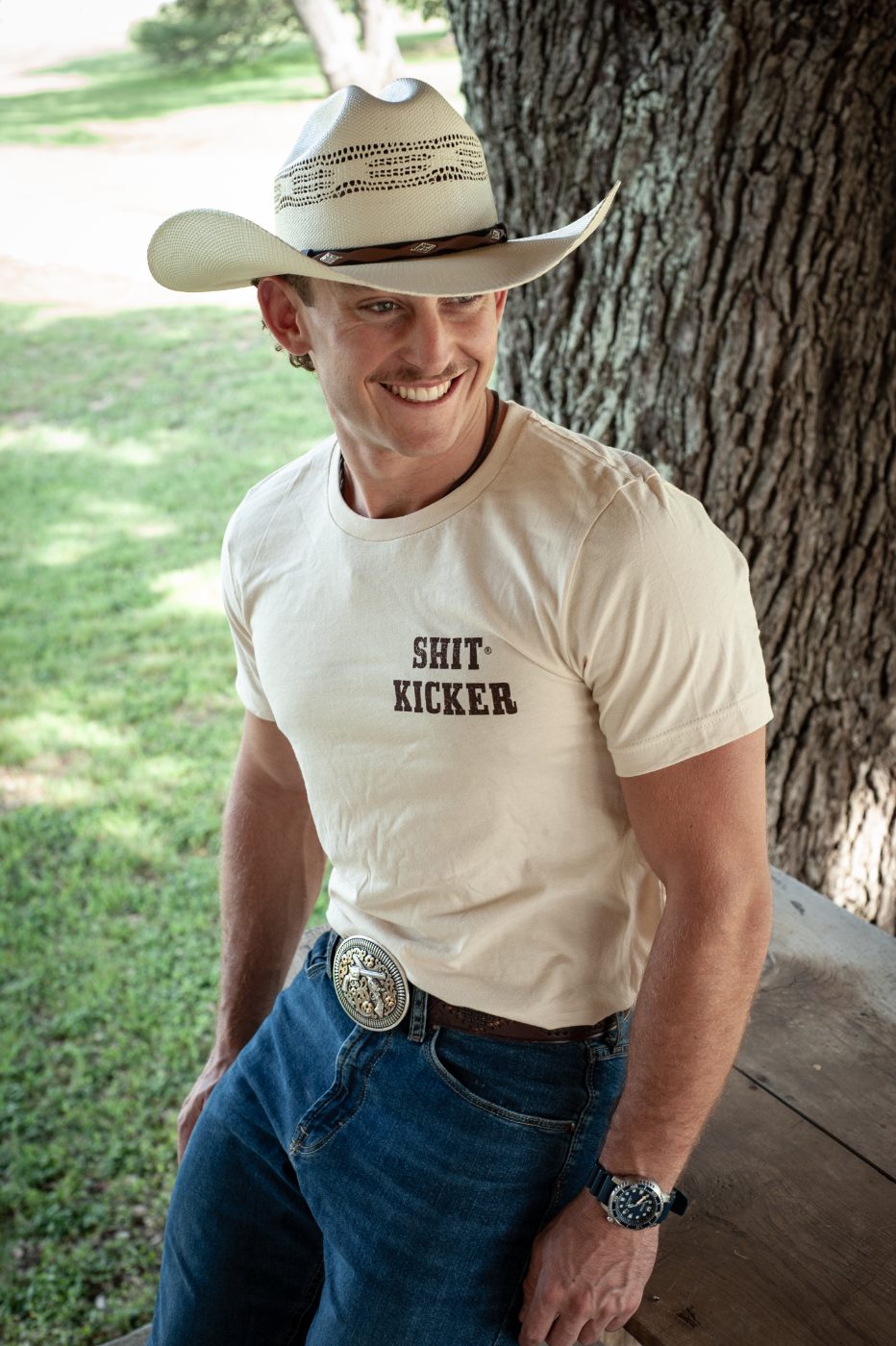 Model in a natural Shit Kicker tee and straw hat